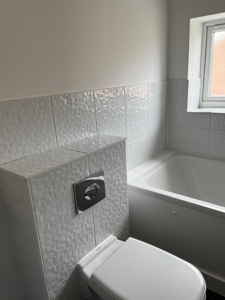 Modern bathroom after a professional deep clean, featuring spotless toilet, bath and textured wall tiles.